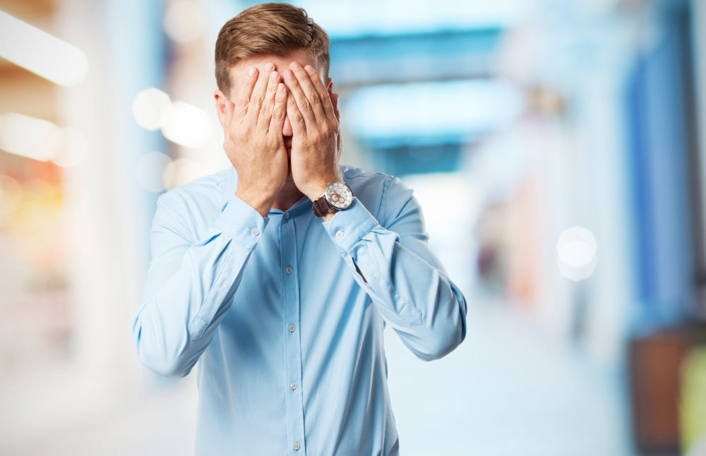 blond man covering face sign